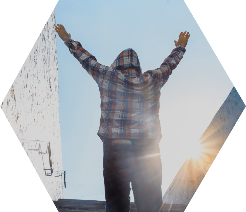person in plaid flannel hoodie on stairs, facing away, with hands in air in triumph