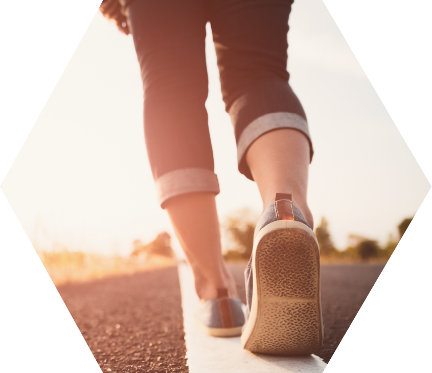 view of the lower legs of woman walking away down middle line of rural road