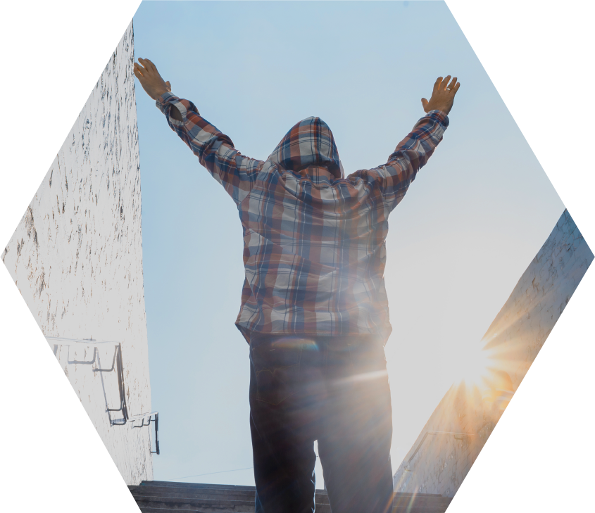 person in plaid flannel hoodie on stairs, facing away, with hands in air in triumph